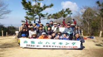 「お菊山ハイキング」と書かれた幕を持って撮影した集合写真