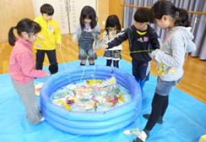 ビニールプールで釣り遊びをしている子供たちの写真