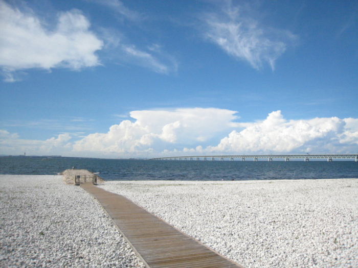 青空に白い雲。砂浜から一直線に歩いて行ける木の板が並び奥にはコバルトブルーのマーブルビーチの風景写真