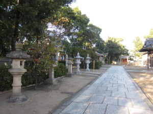 石畳の左側に樹木に覆われた灯籠が並んでいる春日神社の写真