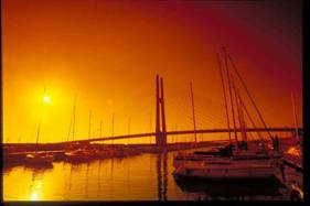 夕焼けの中浮かび上がる田尻スカイブリッジとマリーナに停泊しているヨットを写した写真