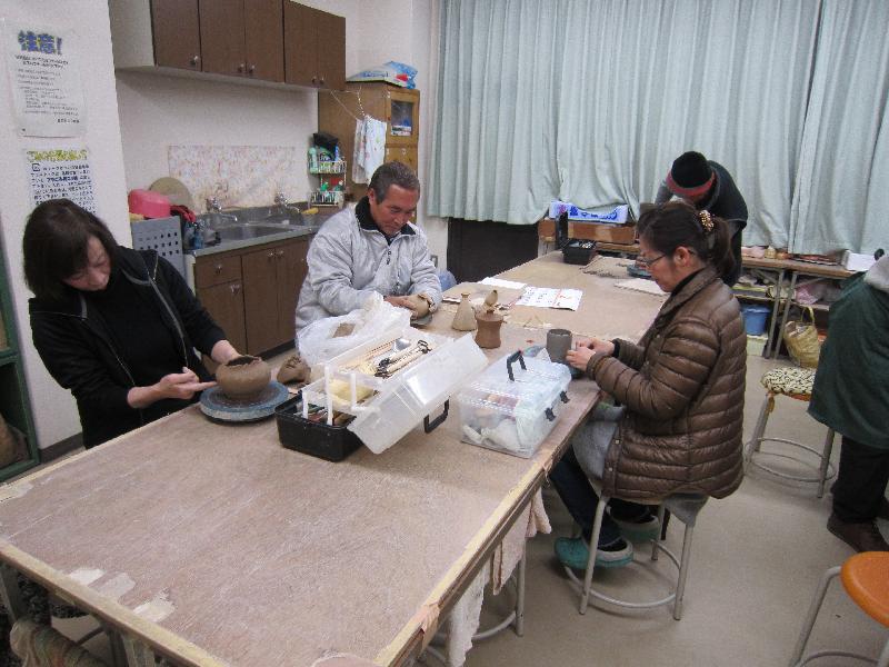 4名の人達が机の上でとくろを使い陶芸を楽しんでいる写真