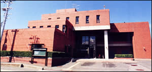 長方形の窓が2階、3階部分に並び、茶色の外壁をした公民館の外観写真