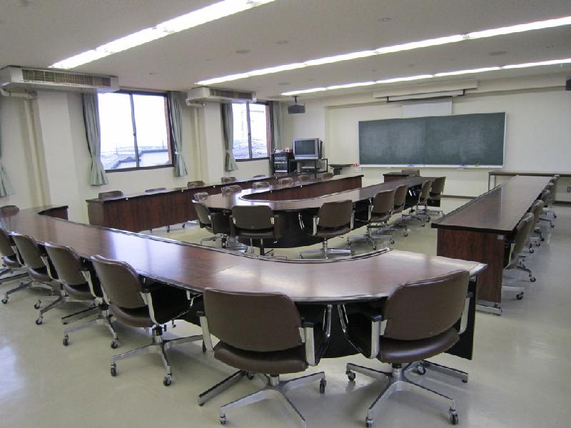 黒板の前にコの形で机が配置され、その中にも机が配置されている視聴覚室の室内の写真