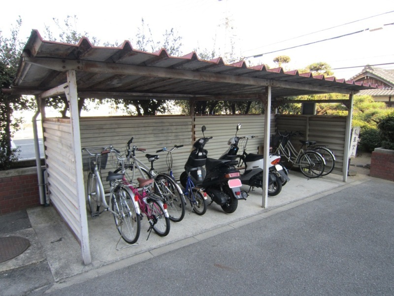 自転車やバイクが停まっている雨除けの屋根がついている駐輪場の写真