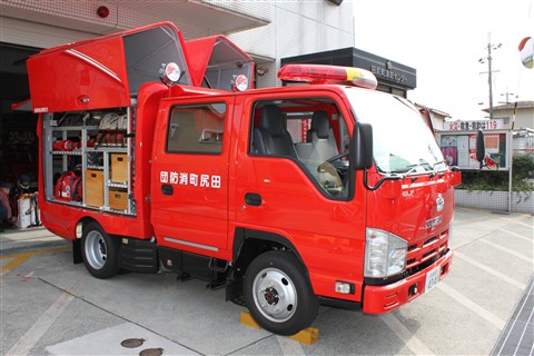 田尻町消防団と後部座性の扉に書かれた真っ赤な消防車の後ろが開いて道具が見えている写真