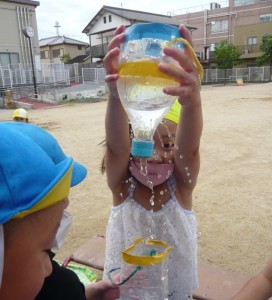 ペットボトルの容器を使って水遊びをしている園児たちの写真