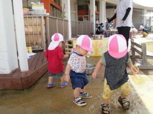 水たまりに入って水遊びをしている園児たちの写真