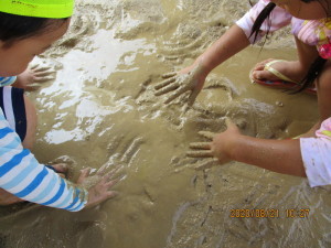 泥の中に手を入れて遊んでいる子供たちの写真