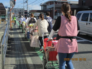 園児をのせた避難用カートを押して歩道を歩いている先生の写真