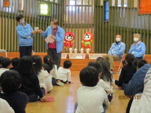 立って話をしている2名の人権擁護委員さんと椅子に腰かけている2名の人権擁護委員さん、座って話を聞いている園児たちの写真