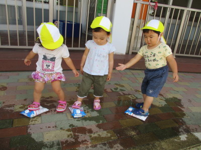 牛乳パック水鉄砲で遊んでいる3人の園児たちの写真