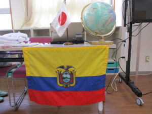 日の丸国旗と地球儀が置かれたテーブルに掛かっているエクアドルの国旗の写真