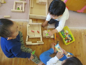 積み木を組み立てて遊んでいる3人の園児たちの写真