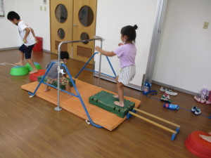 鉄棒やマットを使ってサーキット運動をしている園児たちの写真