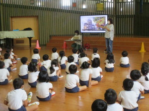 原爆ドームが映し出されたモニター画面を見ている園児たちを後ろから写した写真