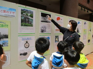 パネルに展示された資料を見ている先生と園児たちの写真