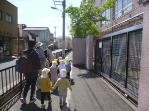 手をつないで並んで歩道を歩いている園児と先生の写真