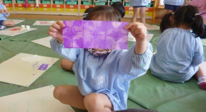 紫色に染まって模様ができた紙を広げて見せている園児の写真