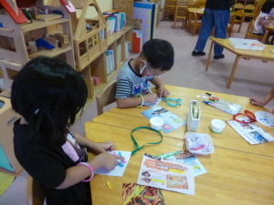 ペンやテープを使ってメダルを作っている2人の園児の写真