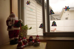 クリスマスツリーの飾り付けがされた窓とサンタクロースの人形の写真