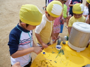 青い絵の具を使って色水を作っている園児たちの写真