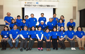 お揃いの青いシャツを着たスマイル元気トライ活動のメンバーの集合写真
